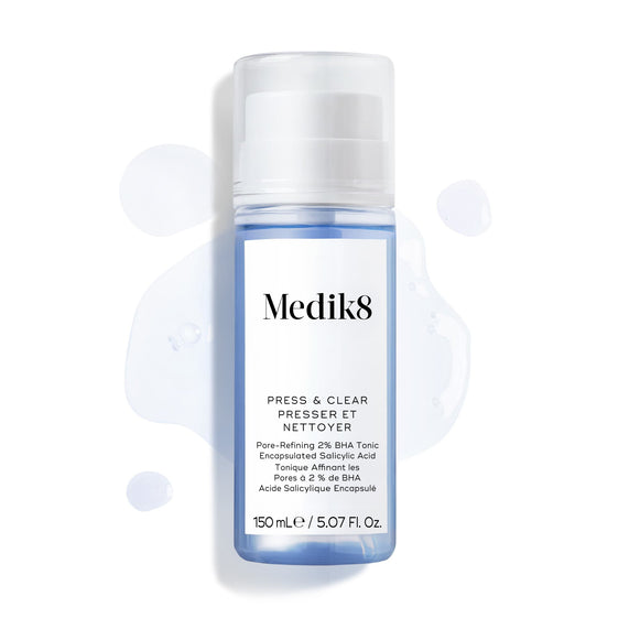 Butelka Medik8 Press & Clear (150 ml) na białym tle z rozbryzgami niebieskiego toniku wokół produktu. Grafika podkreśla formułę złuszczającego toniku z 2% BHA.-17