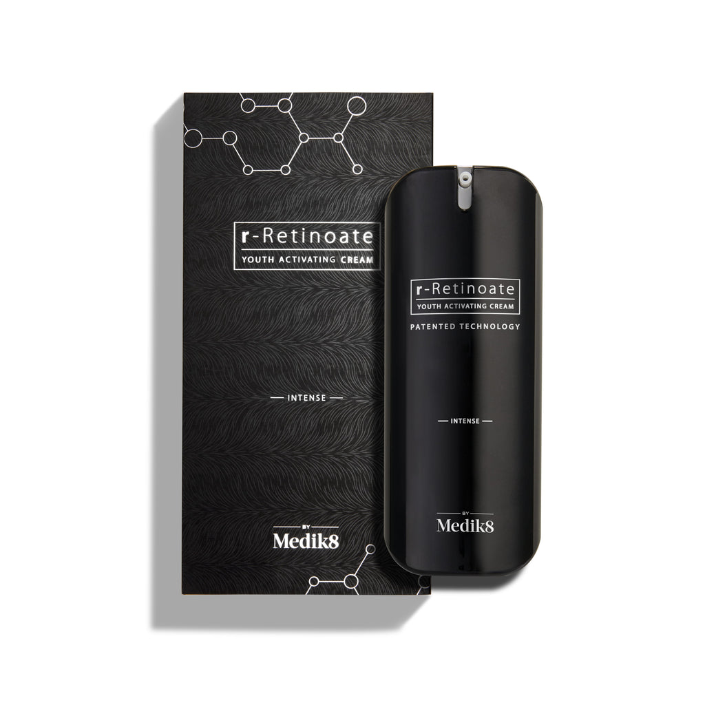 Butelka Medik8 r-Retinoate Intense Youth Activating Cream stoi obok czarnego opakowania zewnętrznego, które zawiera białe graficzne struktury chemiczne w formie heksagonów oraz teksturowany, falisty wzór.
