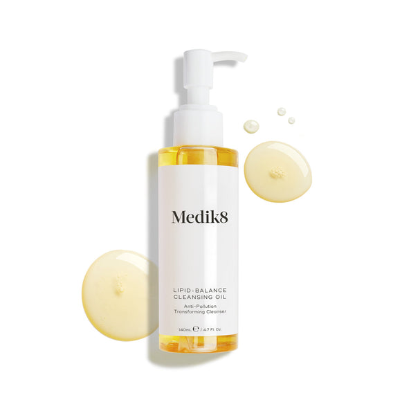 Butelka olejku oczyszczającego Medik8 Lipid-Balance Cleansing Oil stoi na białym tle. Otaczają ją złote kropelki olejku, podkreślające jego gęstą, płynną konsystencję.-19