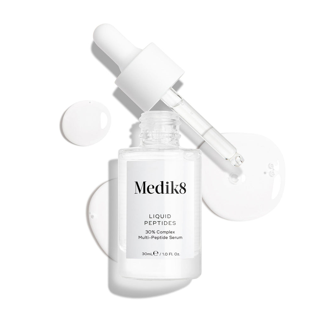 Przedstawiono przezroczystą szklaną buteleczkę z serum Liquid Peptides z zakraplaczem, który został wyjęty i leży obok niej, a także krople serum, które pokazują konsystencję produktu