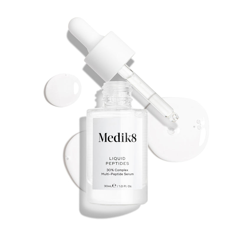 Przedstawiono przezroczystą szklaną buteleczkę z serum Liquid Peptides z zakraplaczem, który został wyjęty i leży obok niej, a także krople serum, które pokazują konsystencję produktu