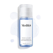 Butelka Medik8 Press & Clear (150 ml) na białym tle z rozbryzgami niebieskiego toniku wokół produktu. Grafika podkreśla formułę złuszczającego toniku z 2% BHA.
