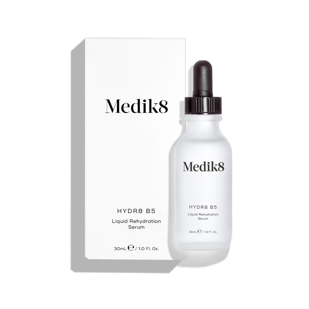 Butelka serum Medik8 Hydr8 B5 stoi przed dopasowanym do niej białym opakowaniem kartonowym na czystym białym tle. Napisy na obu elementach wskazują, że jest to 30-mililitrowe płynne serum nawilżające.