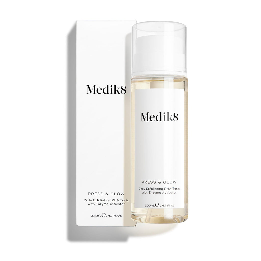 Butelka toniku Medik8 Press & Glow stoi przed dopasowanym białym opakowaniem kartonowym na czystym białym tle. Tekst na obu opakowaniach identyfikuje produkt jako 200 ml codzienny złuszczający tonik PHA z aktywatorem enzymatycznym.
