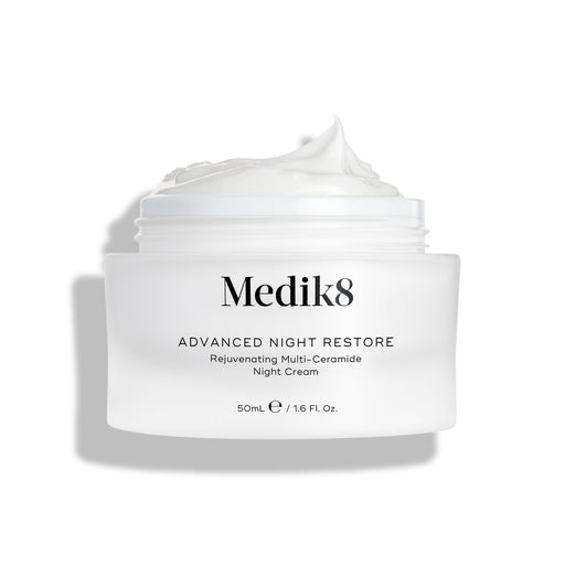 Słoiczek z kremem Medik8 Advanced Night Restore przedstawiony w pozycji otwartej, z obfitą porcją białego kremu uformowaną w kopczyk na wierzchu, na tle czystej bieli, co podkreśla jego gładką, regenerującą konsystencję. Na słoiczku widnieje czarny napis: „Rejuvenating Multi-Ceramide Night Cream”.