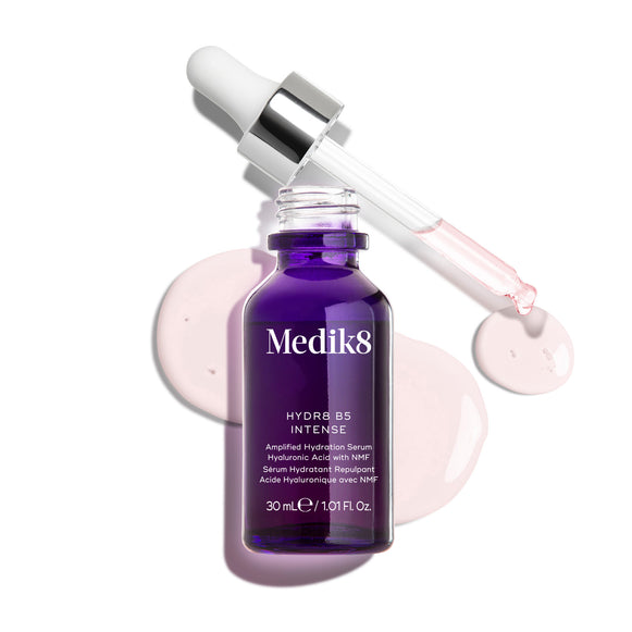 Fioletowa szklana butelka z pipetą Medik8 Hydr8 B5 Intense przedstawiona na czystym białym tle, z otwartą pipetą umieszczoną nad jasnoróżowymi kroplami serum. Tekst podkreśla, że formuła zawiera kwas hialuronowy oraz NMF (Natural Moisturising Factors), które pomagają nawilżać i wzmacniać skórę, w rozmiarze 30 ml.
-12