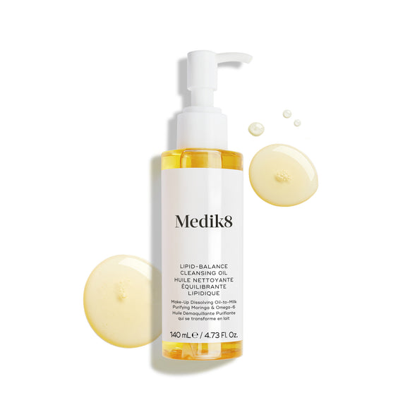 Butelka olejku oczyszczającego Medik8 Lipid-Balance Cleansing Oil stoi na białym tle. Otaczają ją złote kropelki olejku, podkreślające jego gęstą, płynną konsystencję.-23